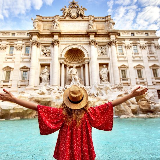 Beautiful woman in front of famous iconic Trevi Fountain at Rome, Italy.