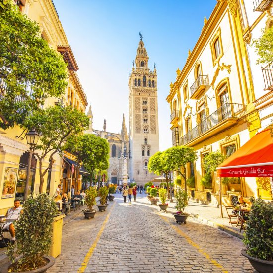 Seville, Spain - 6 March 2020: Sunny Seville street and scenic view of Giralda tower