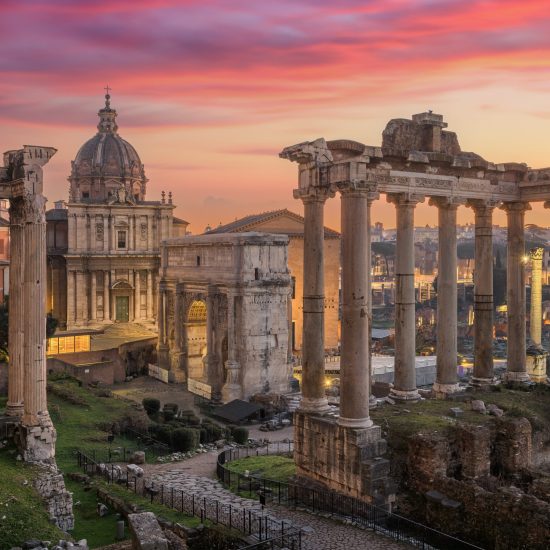 Rome, Italy at the historic Roman Forum ruins at dusk.
