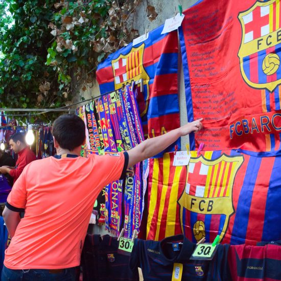 "Barcelona, Spain-april 21, 2012 :man is showing by his hand to the flag of FC Barcelona at the street shop, situated close to the stadium Camp Nou in Barcelona"
